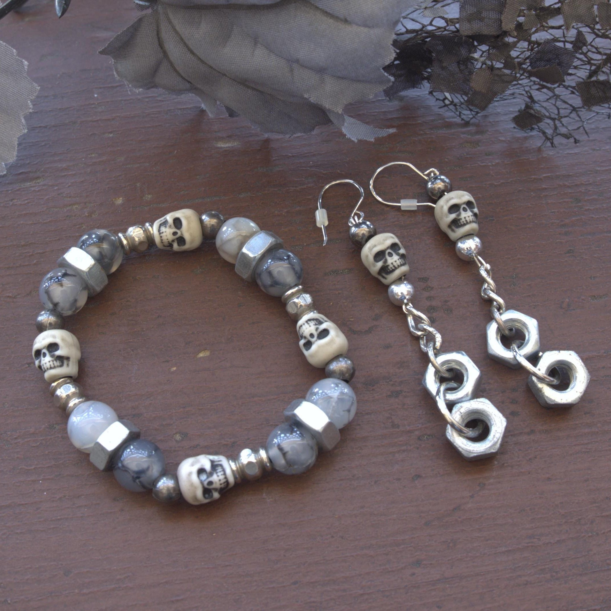Skull-themed bracelet and earrings on a wooden surface