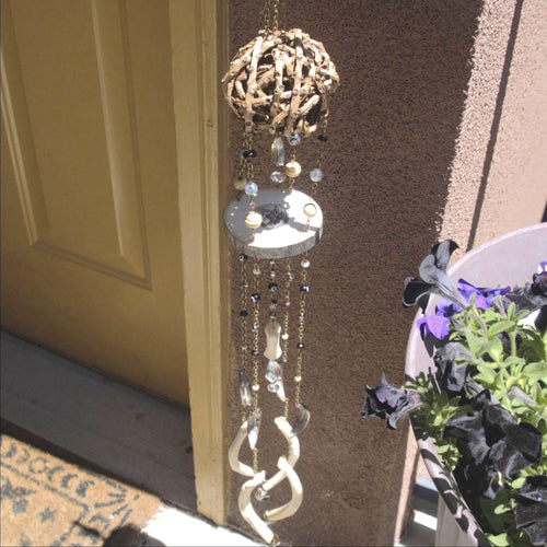 Decorative wind chime hanging on a door with a plant in the foreground