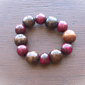 Beaded bracelet with red and brown beads on a wooden surface