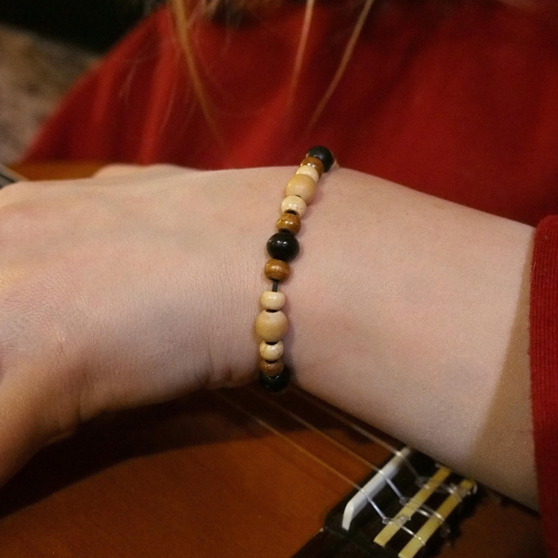 Person playing guitar with a beaded bracelet on wrist