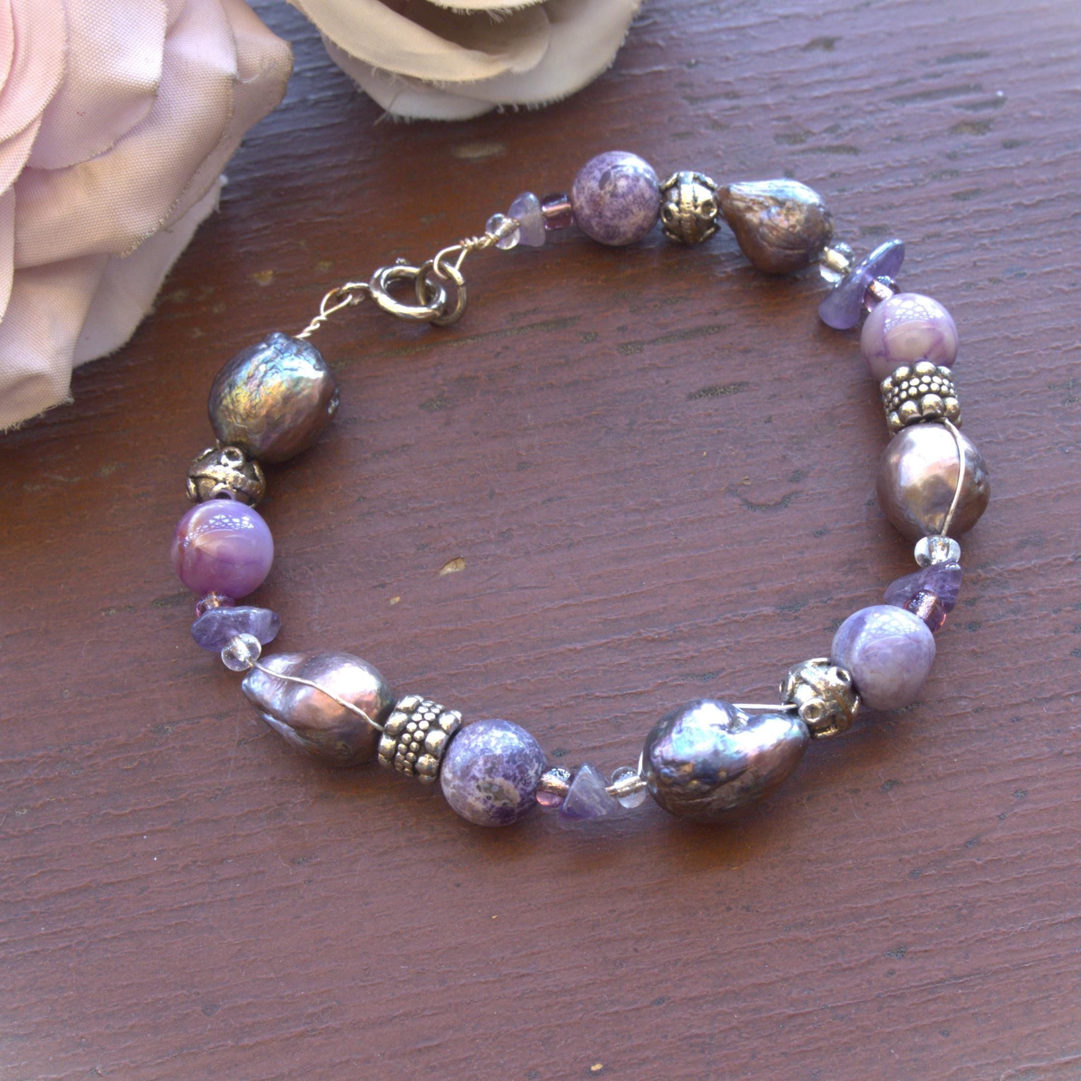 Purple beaded bracelet on a wooden surface with flowers in the background