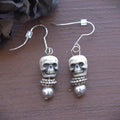 Skull-shaped earrings with beads on a wooden surface